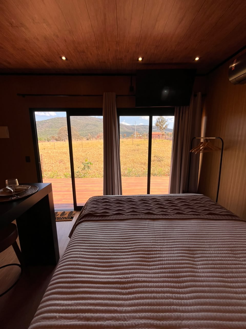 Cama voltada para as portas de vidro com vista para o campo e a serra