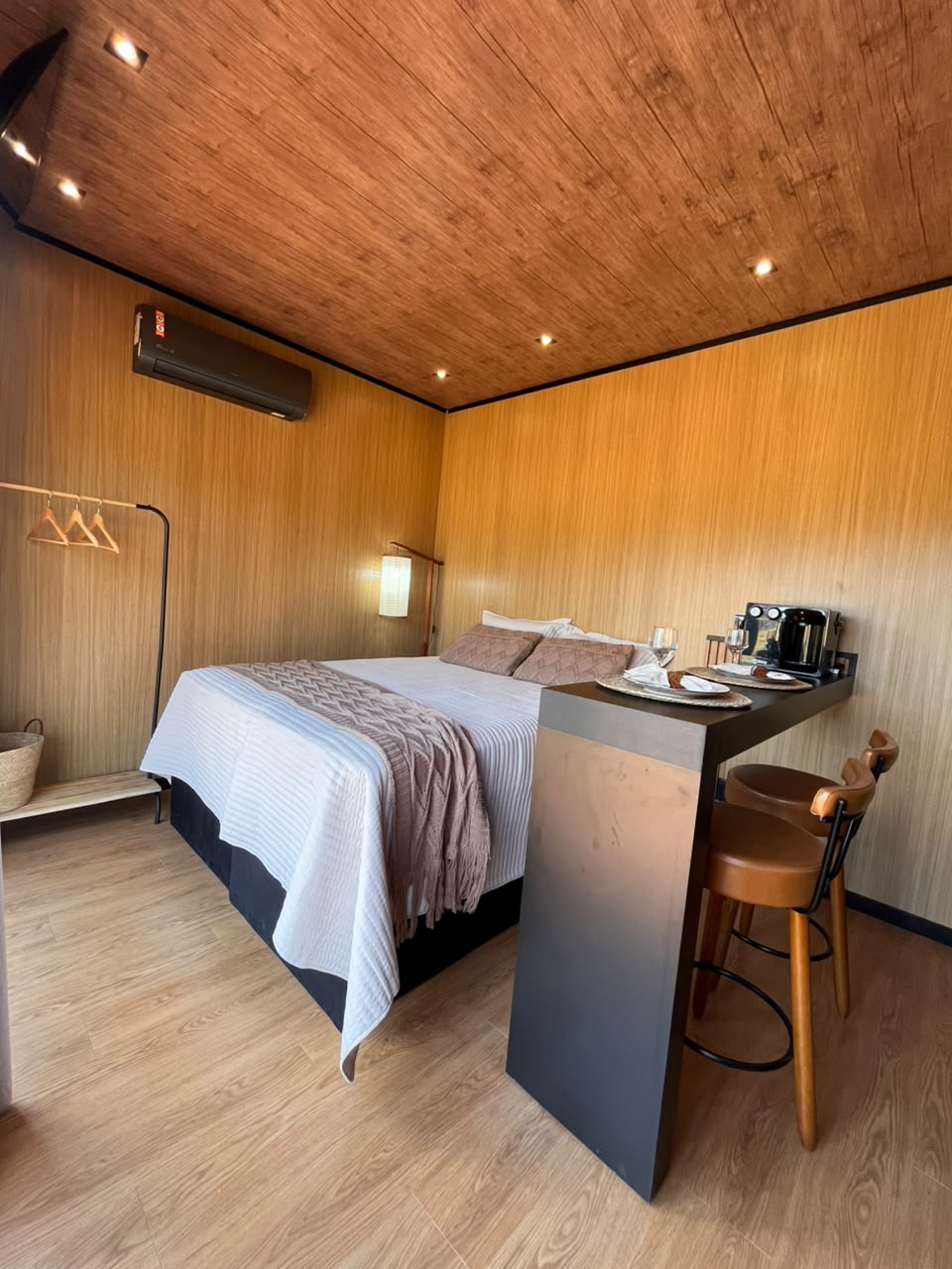 Cama de casal com manta e bancada de refeições ao lado